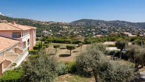 Un quartiere residenziale su una collina, con case e un edificio rosa ben visibile con un balcone, sotto un cielo azzurro limpido.