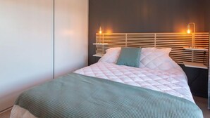Ein modernes Schlafzimmer mit einem Bett, Nachttischen und einer Wandleuchte.
