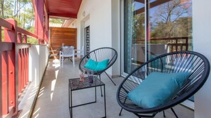 Ein Balkon mit zwei Korbstühlen, einem kleinen Tisch und einer Holzterrasse.