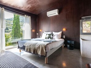 Een moderne slaapkamer met een groot bed, uitzicht op de omgeving en een ingebouwde airconditioning.