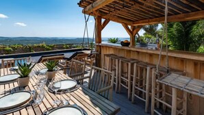 Eine Holzterrasse im Freien mit Tischen und Stühlen, mit Blick auf eine schöne Landschaft.