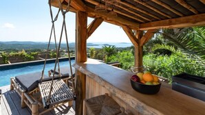 Eine Holzterrasse mit Pool, Schaukelstuhl und Obstschale.
