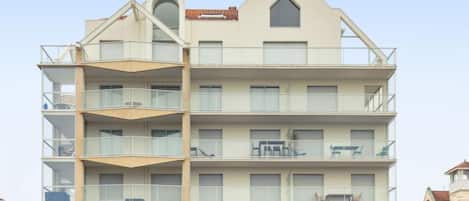 A multi-story building with balconies, large windows, and a distinct architectural design.