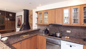 A modern kitchen with wooden cabinets, granite countertops, a built-in oven, and a black stove.