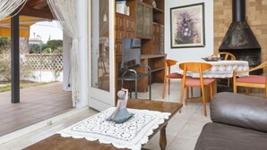 A cozy living room with a fireplace, a television, and a dining area with chairs and a table.