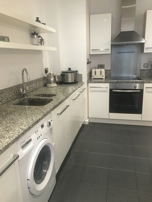 Fully equipped kitchen with granite countertop, stainless steel appliances, and white cabinetry.