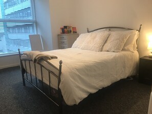 Cozy retreat with a metal-framed bed, bedside table, and bookshelf.