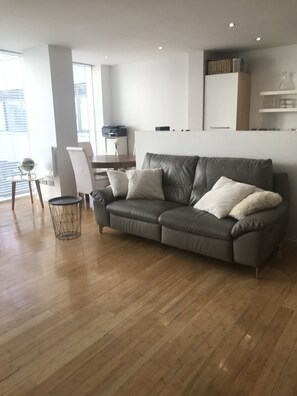 Relax in this stylish living room with a comfortable sofa, wooden floor, and large window.