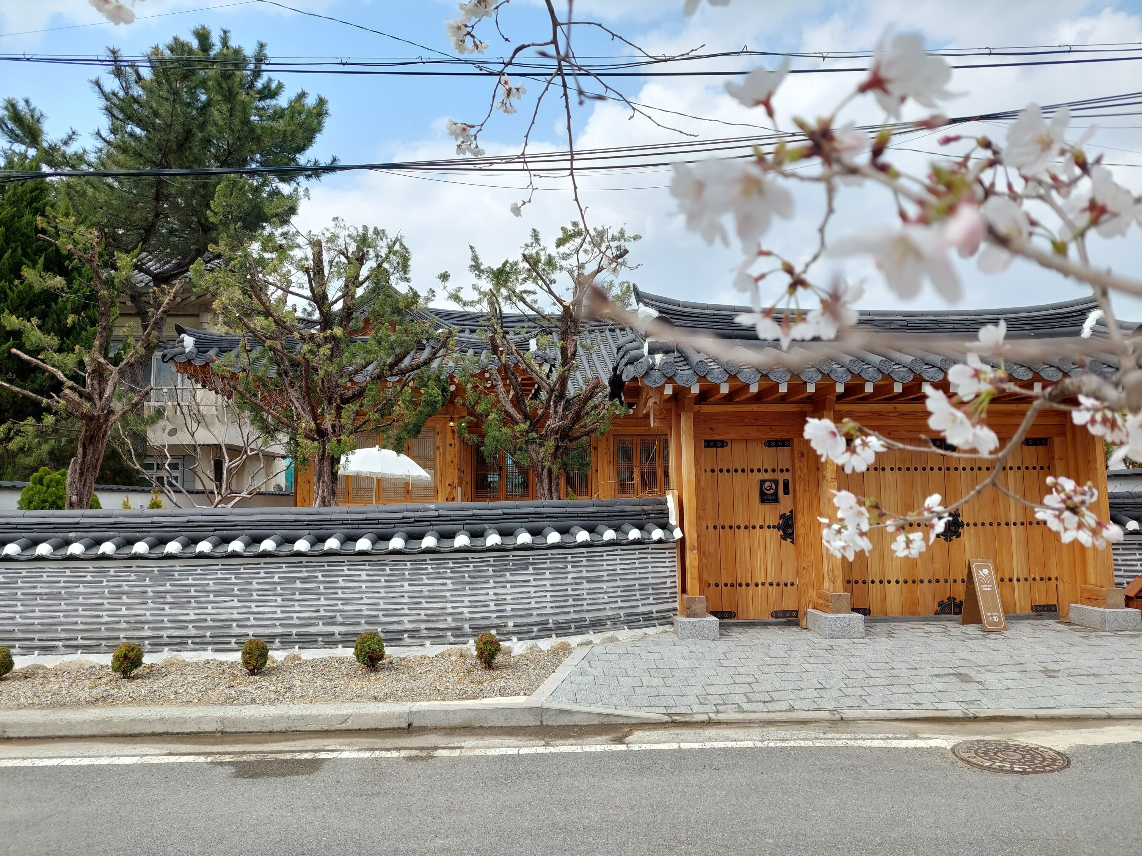 A traditional Japanese building with a wooden entrance, a tiled roof, and a stone wall.