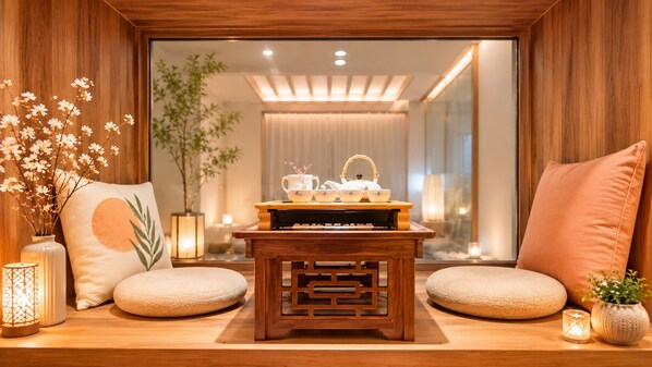 Un coin salon confortable avec une table en bois, des coussins et un service à thé.