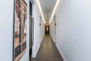 A hallway with a wooden floor, white walls, and a poster of an elephant. - Stylish Hotel Room with Kitchenette (Miami)