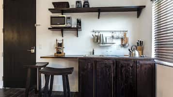 Une cuisine avec des meubles de couleur bois foncé, un four à micro-ondes, une machine à café et un porte-ustensiles suspendu.