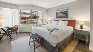 A hotel room with a large bed, a desk, and a view of the mountains. - Grand Lodge CB #518 — Top-Floor Remodel, Ski-In/Out, Pool + Hot Tub (Crested Butte)