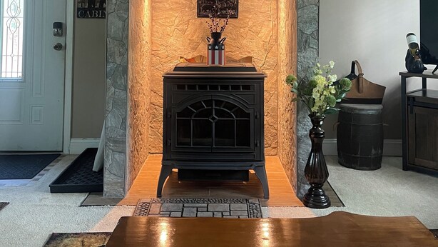 Ein gemütliches Wohnzimmer mit Kamin aus Stein, einem Holztisch und einem Deckenventilator.