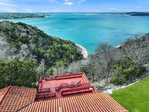 A red-roofed building with a terrace overlooking a turquoise sea and a forested hillside. - Point of View I Canyon Lake access! (Canyon Lake)