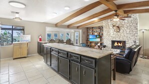 Una cocina amplia con una isla grande, armarios oscuros y una chimenea de piedra.