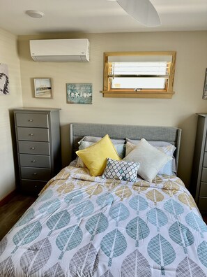 Une chambre à coucher avec un lit, une commode, une fenêtre et des éléments décoratifs sur les murs.