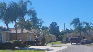 A residential street with houses, palm trees, and a clear blue sky. - Peacefull villa in Lake Marion Golf Resort,all amenite,35' to the park atraccion (Kissimmee)