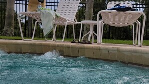 A swimming pool with white lounge chairs and a black bag on the deck. - Peacefull villa in Lake Marion Golf Resort,all amenite,35' to the park atraccion (Kissimmee)