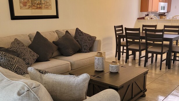 A living room with a sofa, coffee table, and patterned cushions. There is a framed picture on the wall and a ceiling fan in the background. - Peacefull villa in Lake Marion Golf Resort,all amenite,35' to the park atraccion (Kissimmee)