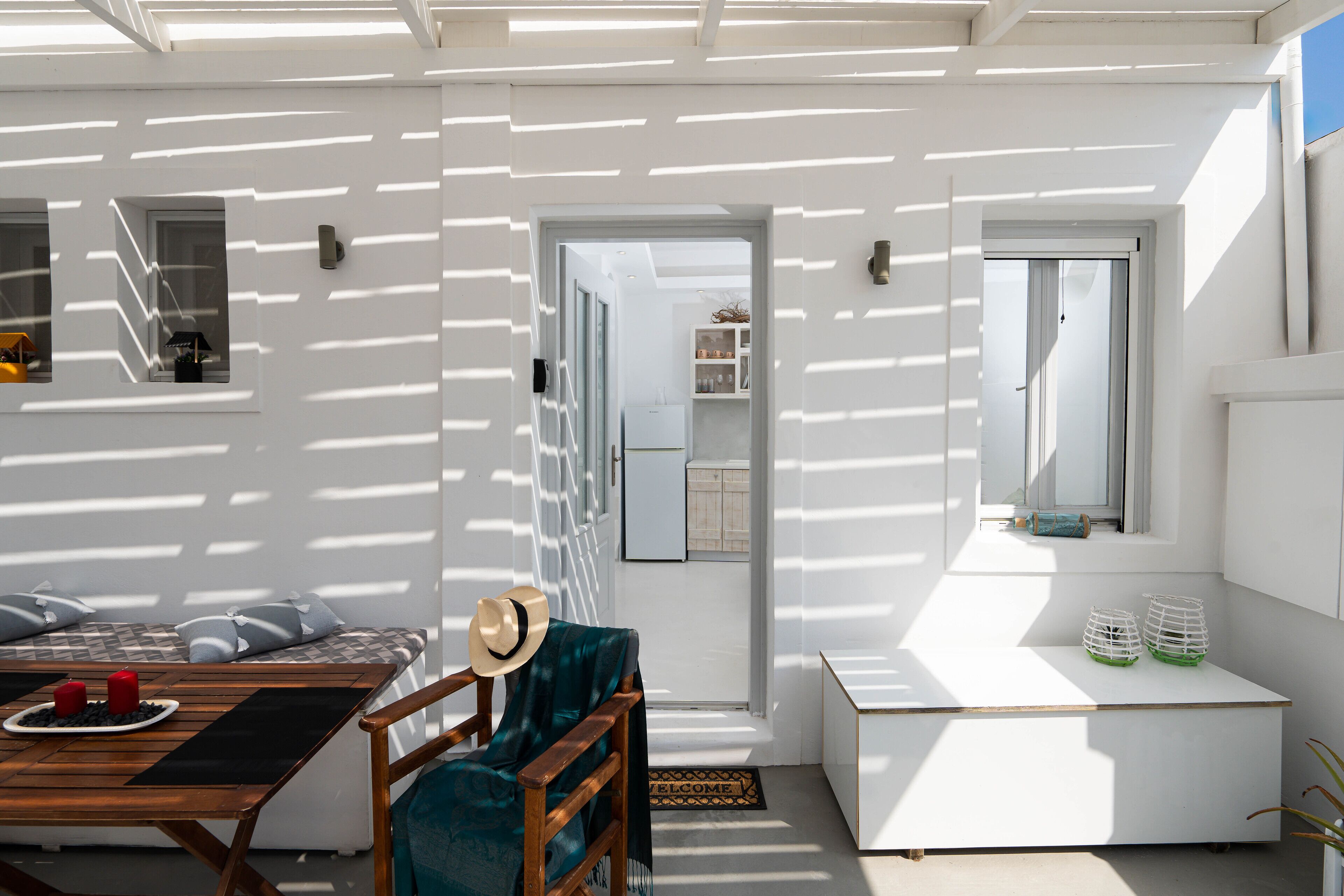 A sunlit room with a wooden table, a chair, a hat, and a bench.