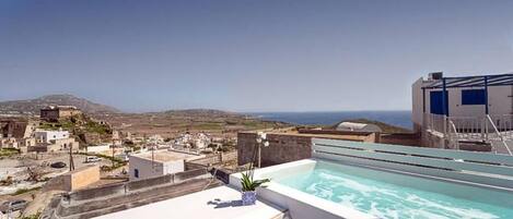 Piscina no terraço com vista ampla dos edifícios e paisagem ao redor.