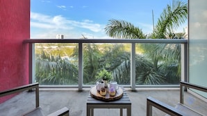 A balcony with a table, chairs, and a view of palm trees and buildings. - Modern Resort w/ Balcony + Near Beach + Pool (Hallandale Beach)