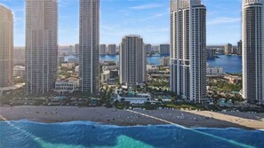A coastal cityscape with high-rise buildings, a beach, and a marina.
