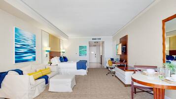 Quarto de hotel com cama, sofá, escrivaninha e mesa de jantar.