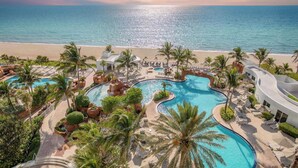 Ein Resort mit mehreren Schwimmbecken, Palmen und Blick auf den Strand.