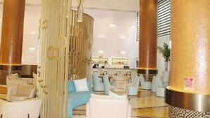 Eine moderne Lobby mit Sitzgelegenheit, einer Rezeption und dekorativen Säulen.