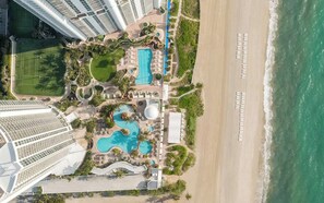 Un resort con diverse piscine, una spiaggia e alti edifici sullo sfondo.