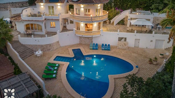 A villa with a swimming pool, outdoor seating, and a multi-level structure with balconies.