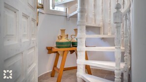 A staircase with white balusters and a wooden handrail, leading to a landing with a door and a window.