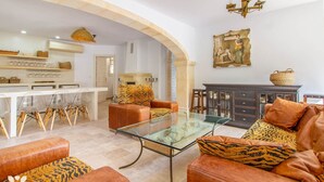 A spacious living area with leather sofas, a glass coffee table, and a dining area with clear chairs.