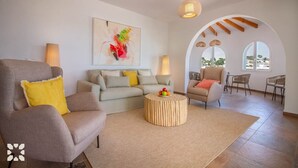 Ein modernes Wohnzimmer mit einer Couch, Sesseln, einem Couchtisch und einem Bild an der Wand.