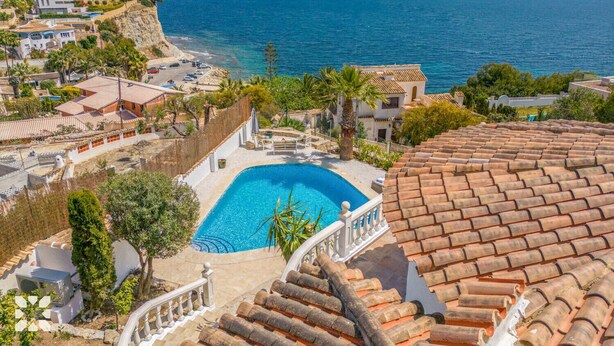 Eine Küstenvilla mit Pool, Terrakotta-Dach und Blick auf den Ozean.