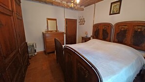 A bedroom with a wooden bed, a dresser, a mirror, and a chandelier. - ANCIENT HOUSE ON THE RIVER (Bagni di Lucca)