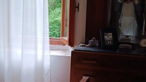 A room with a wooden desk, a clock, and a window with a view of greenery. - ANCIENT HOUSE ON THE RIVER (Bagni di Lucca)