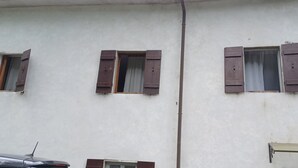 A building facade with three windows, each with wooden shutters, and a visible utility pole. - ANCIENT HOUSE ON THE RIVER (Bagni di Lucca)
