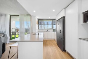 Cozinha moderna com uma ilha grande, geladeira e vista para o exterior.