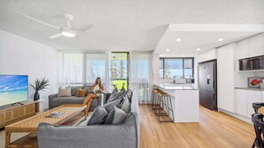 A modern living room with a sofa, a coffee table, a TV, and a ceiling fan.