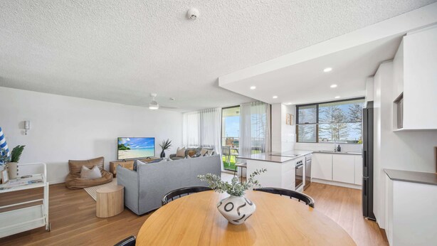 A modern living space with a dining area, kitchen, and a view of the outdoors.