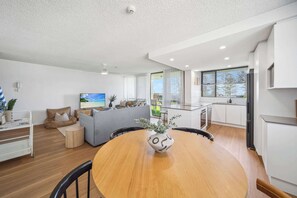 Um espaço de estar moderno com área de jantar, cozinha e vista para o exterior.