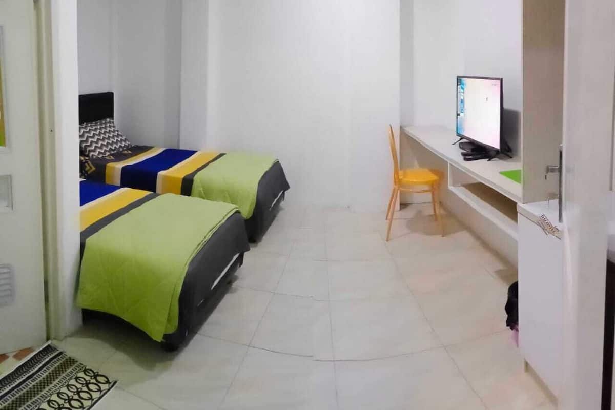 Una habitación pequeña y limpia con dos camas, un escritorio y una silla.