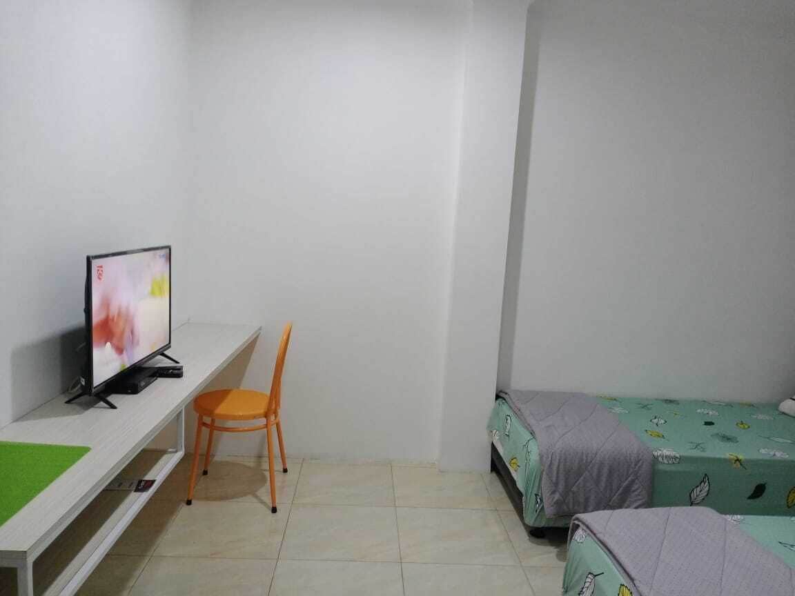 A room with a bed, a chair, a TV, and a desk.