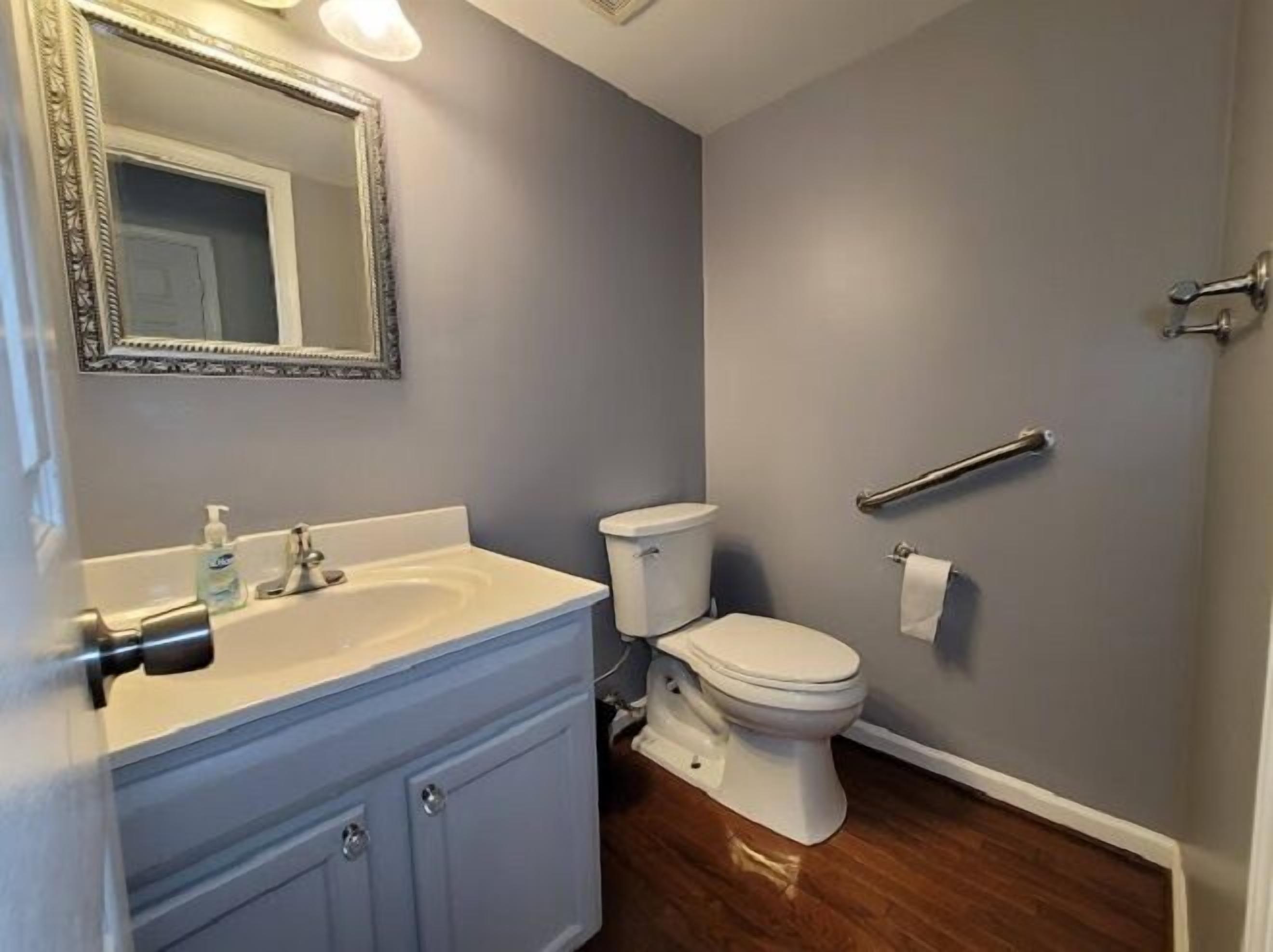 A bathroom with a sink, toilet, and mirror.