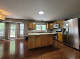 Una cocina amplia con armarios de madera, un refrigerador de acero inoxidable y una isla grande.