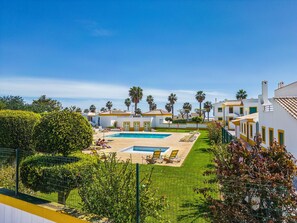 A pool area with two pools, surrounded by palm trees and a well-maintained lawn. - Nuances do Oceano OCV - Pool and parking (Albufeira)