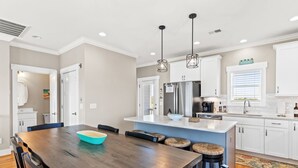 A modern kitchen with a central island, white cabinetry, and pendant lighting. - Fore Seasuns / 139 Scotch Bonnet Dr. 4 Bedroom Home by RedAwning (Supply)